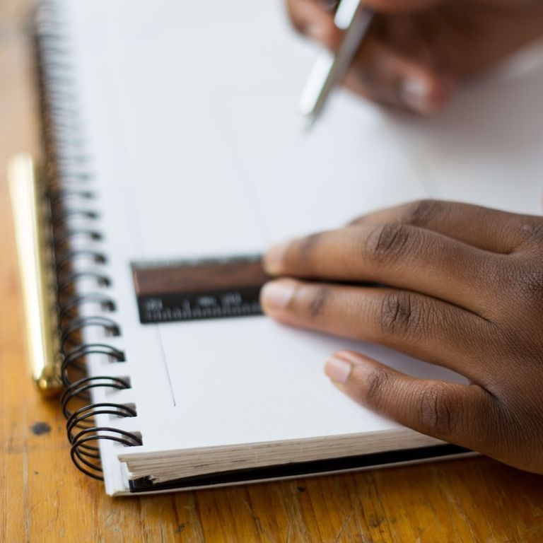 Picture of a person using a ruler to draw a line in a notebook